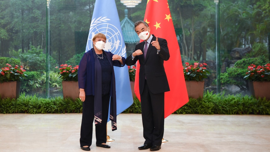 Michelle Bachelet and Wang Yi pose for a photo while bumping elbows. 