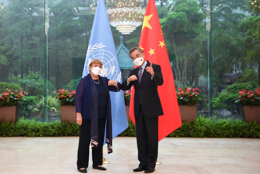 Michelle Bachelet and Wang Yi pose for a photo while bumping elbows. 