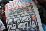 Relatives of dead taxi driver hold up newspapers