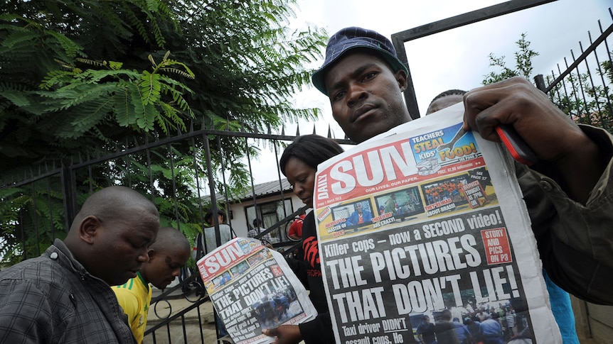 Relatives of dead taxi driver hold up newspapers