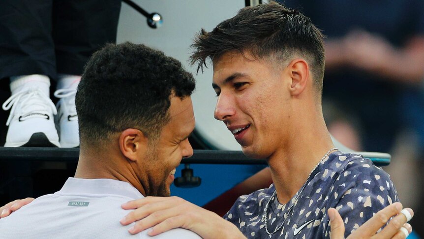 Alexei Popyrin puts his hands on Jo-Wilfried Tsonga's shoulders as they embrace at the net after an Australian Open match.