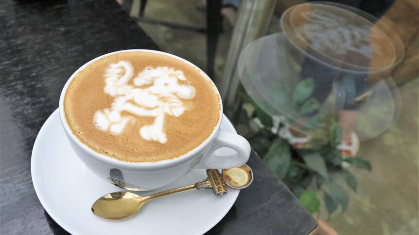 A cup of coffee featuring latte art of a poodle.