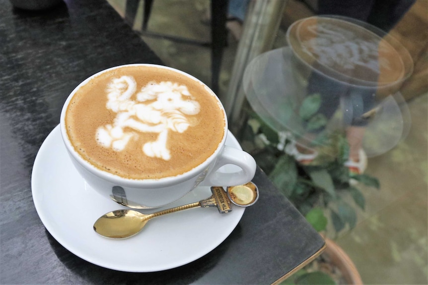 A cup of coffee featuring latte art of a poodle.