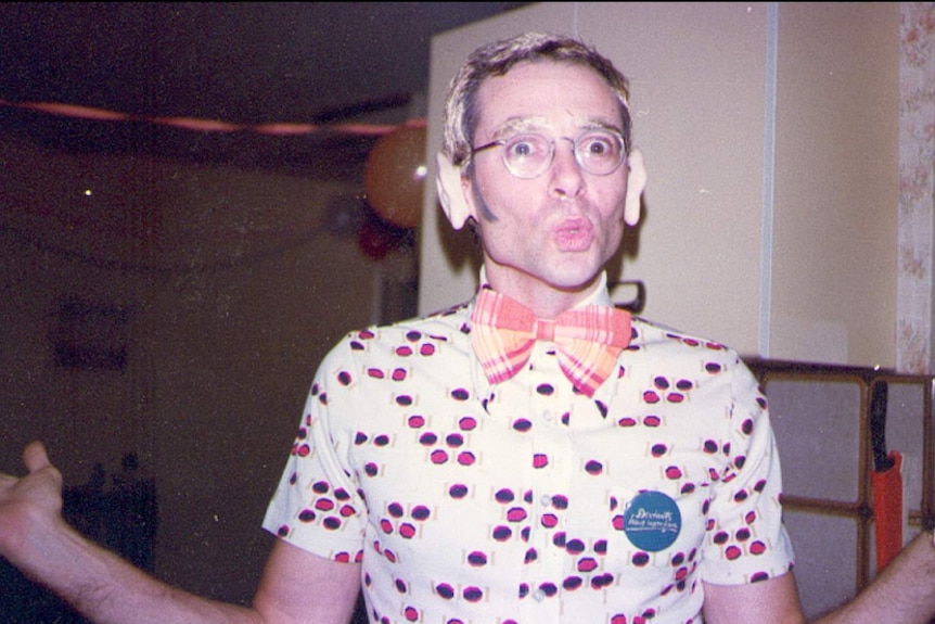 A man wearing fake ears and a bow tie pulls a face.