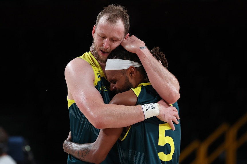 Joe Ingles hugs Patty Mills after Australia won the bronze-medal basketball game against Slovenia at the Tokyo Olympics.