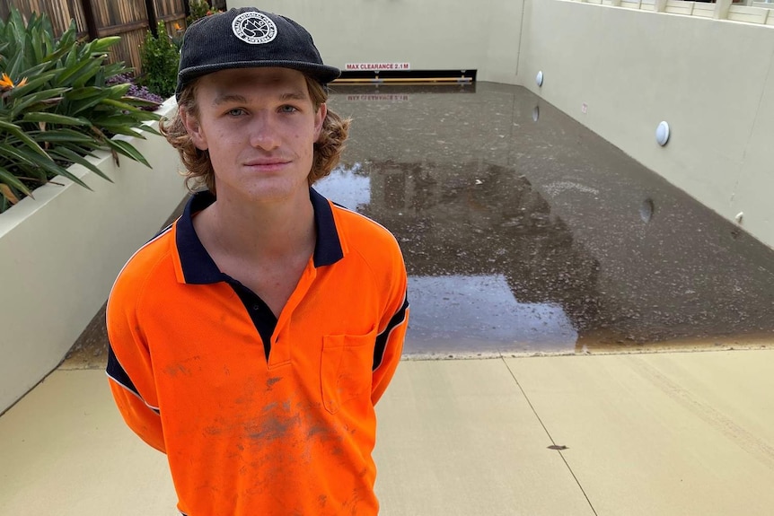 Huntley Lavender-Webb stands outside his apartment block at driveway of flooded underground car park.