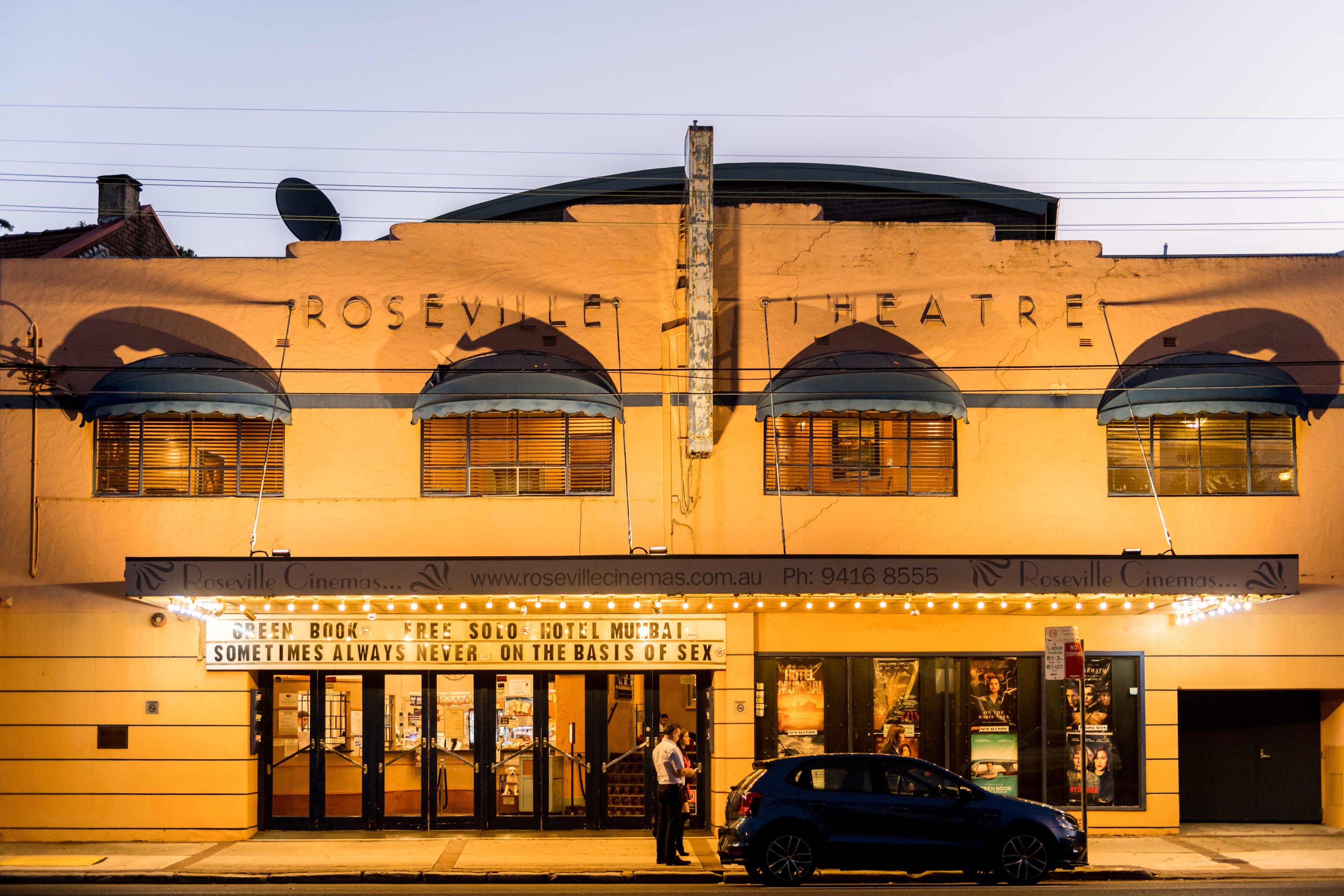 Una foto nocturna de Roseville Cinemas en Roseville de Sydney en 2019, con un hombre y un auto negro en el frente.