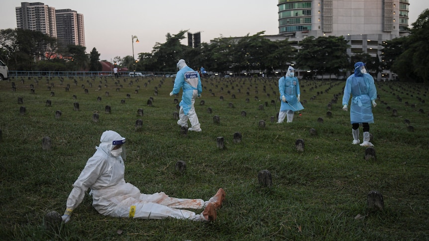 Health workers in PPE take a break while burying bodies of COVID-19 victims 