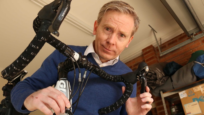 Damien O'Donovan leans over the handlebars of his bike, looking into camera.