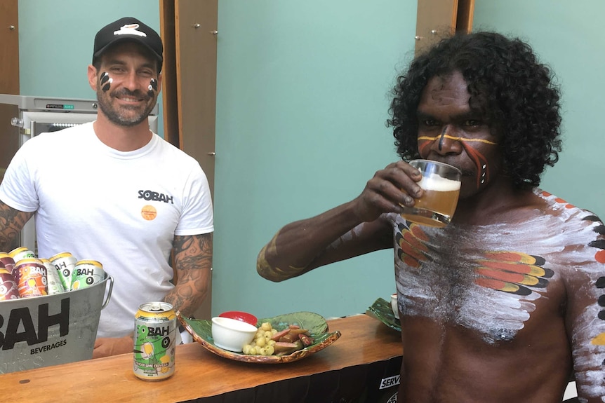 Psychologist Clinton Schultz smiles as Indigenous dancer Warrick Newbury drinks alcohol-free beer.