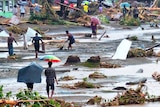 People walk through debris resulting from days of heavy rain in the Solomon Islands.