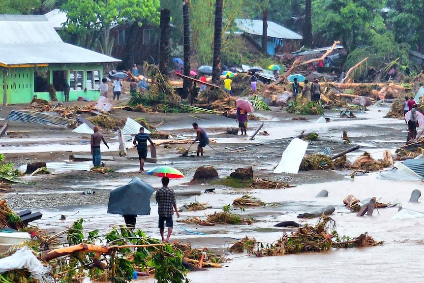 People walk through debris resulting from days of heavy rain in the Solomon Islands.