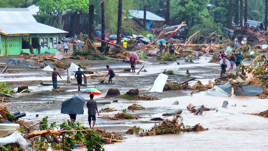 People walk through debris resulting from days of heavy rain in the Solomon Islands.