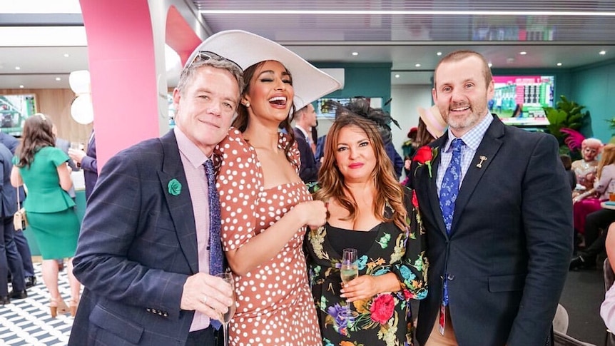 Two men and two women standing in fancy dress smiling.