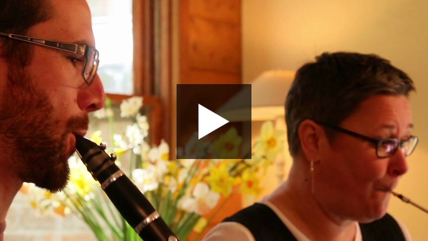 A bassoon player and a clarinet player performing in a living room.