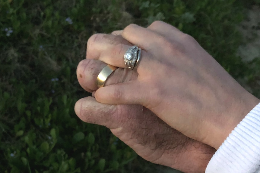 Man and woman's hands joined, wearing wedding rings