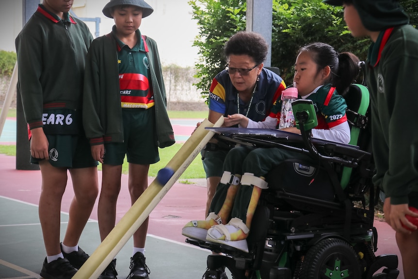 student in a wheelchair pushes the boccia down a ramp