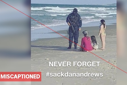 A dressed-in-black police office speaking with a mother and her children on the beach.