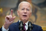 Joe Biden speaks into two microphones and points forwards.