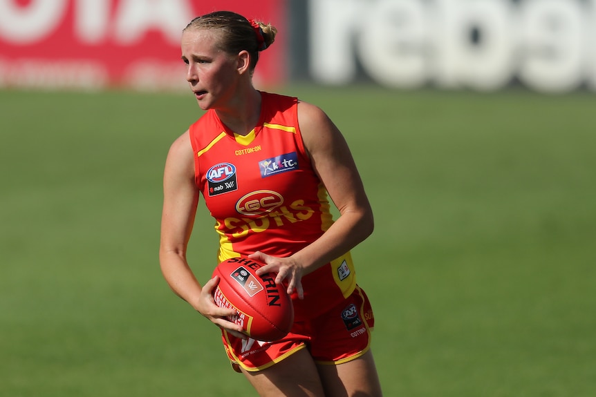 Daisy D'Arcy looks to pass the ball during an AFLW game.