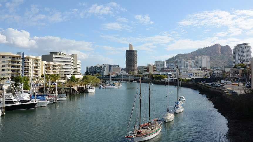 Boats on a river with a marina on one side and a wharf on the other.