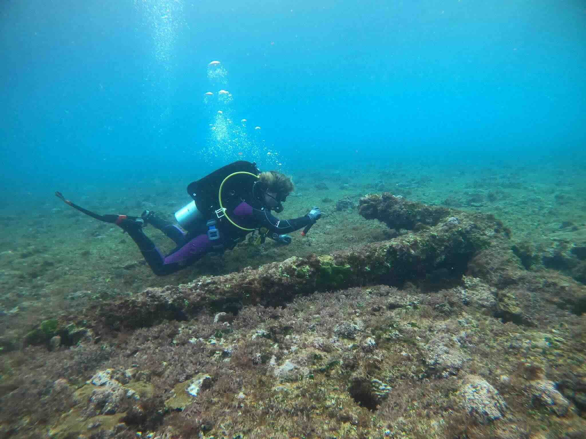 A scuba diver underwater near a large anchor