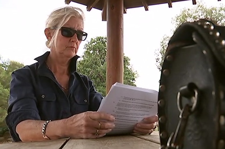 Rose Pizzini, a former fruit picker and cleaner reads documentation at an outdoor table.