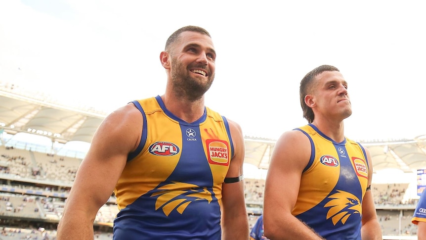 West Coast Eagles players Jack Darling and Jake Waterman walk off the ground looking happy after a win.