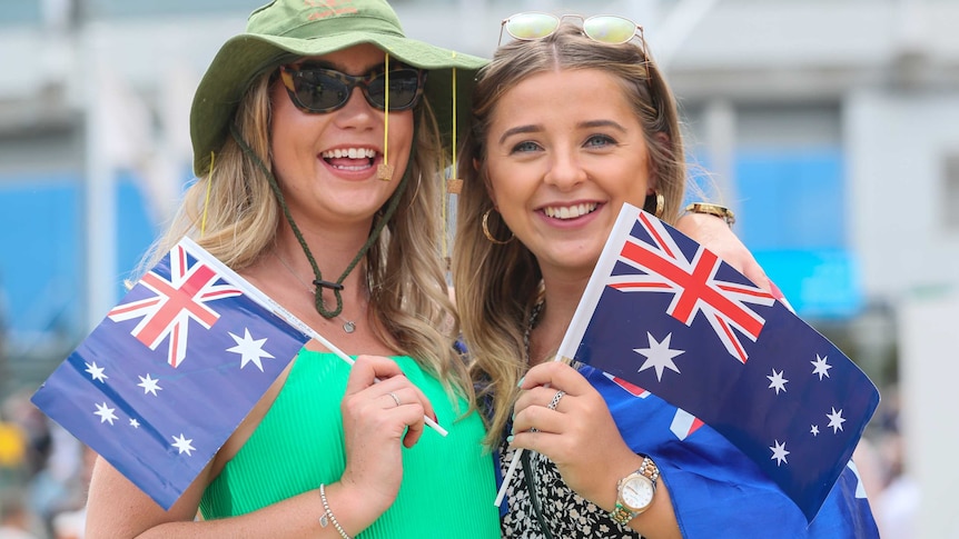 Two women are smiling and holding Australian flags