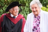David Bottomley smiles wearing his university graduation gown while looking at his wife Anne.