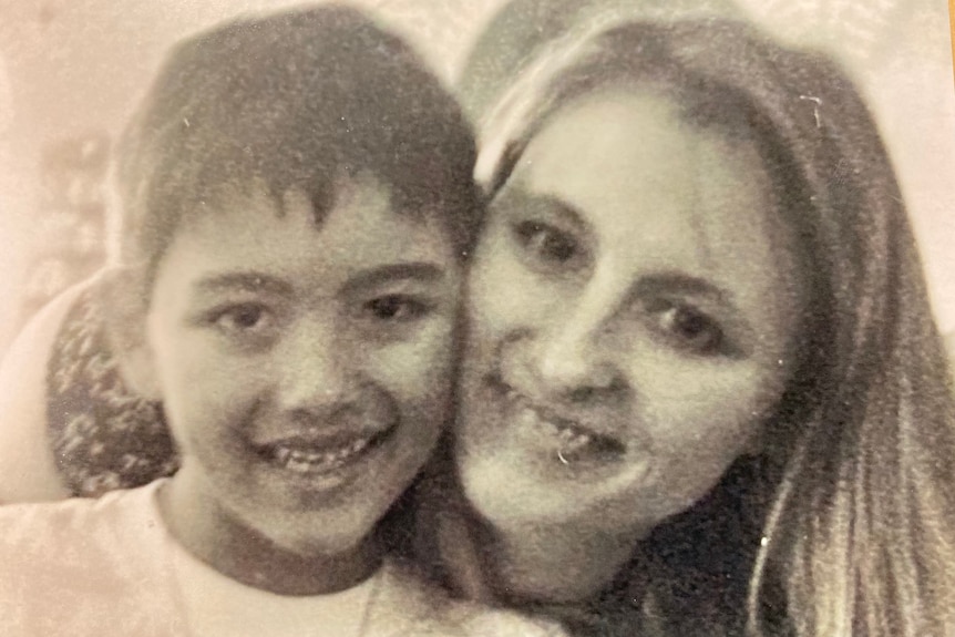 A black and white picture of a young Jesse Vikelis-Curas, hugged by his mother Kristina