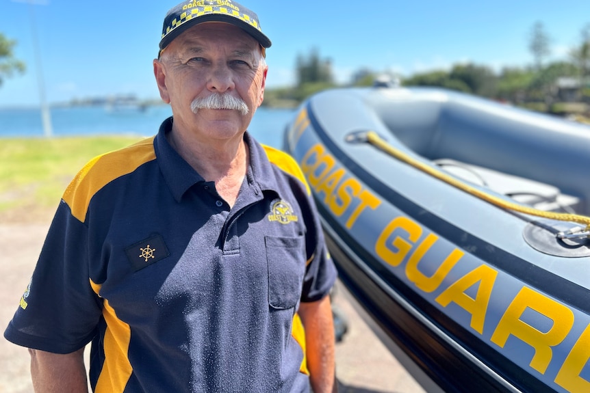 A uniformed man standing next to a small rescue boat.