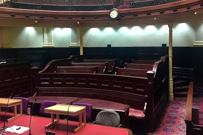 Wooden tables and chairs inside a courtroom in Sydney.