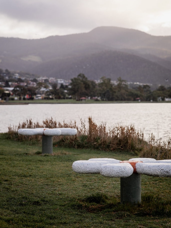 two daisy shaped sculptures on the bank of a river