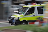 An ambulance speeds down a road.