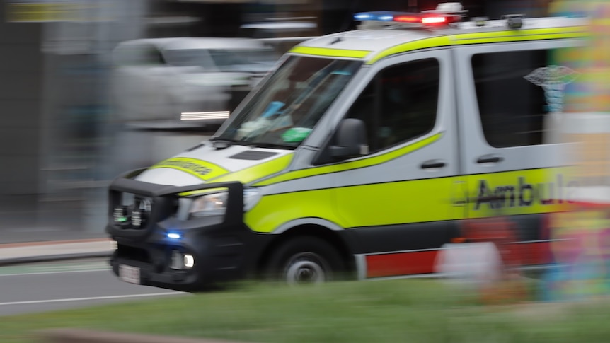An ambulance speeds down a road.
