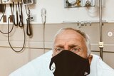 Greg Norman lying in a hospital bed wearing a face mask after feeling COVID-19-like symptoms on Christmas Day.