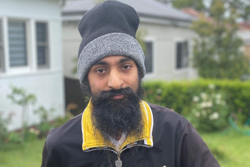 Man with a beard in front of a house