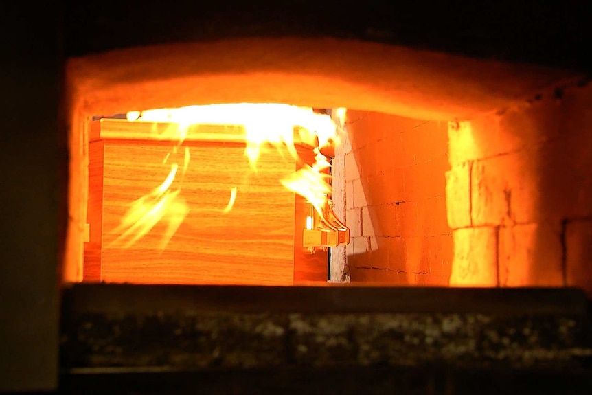 A coffin being cremated in a crematorium.