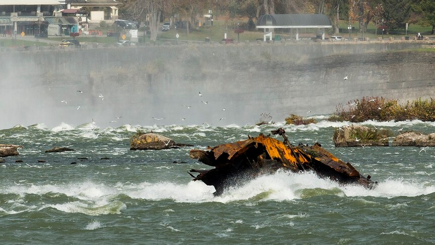 Shipwreck in the falls with houses in the background.