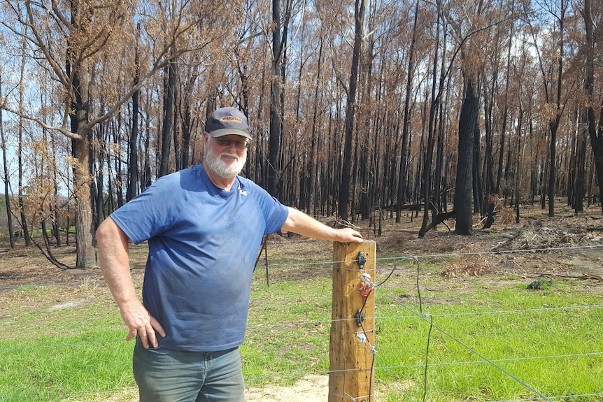 Ross Walker and one of his fixed fenceposts, burnt bush in the background
