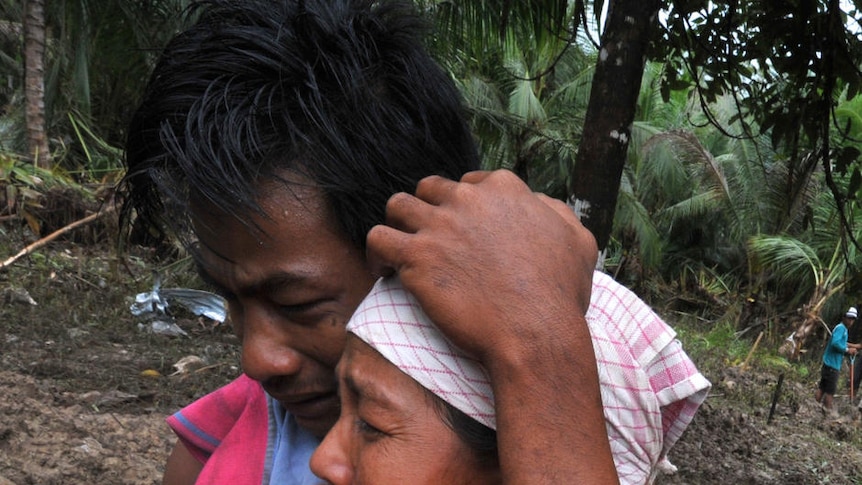 Survivors on North Pagai island mourn next to their relatives.