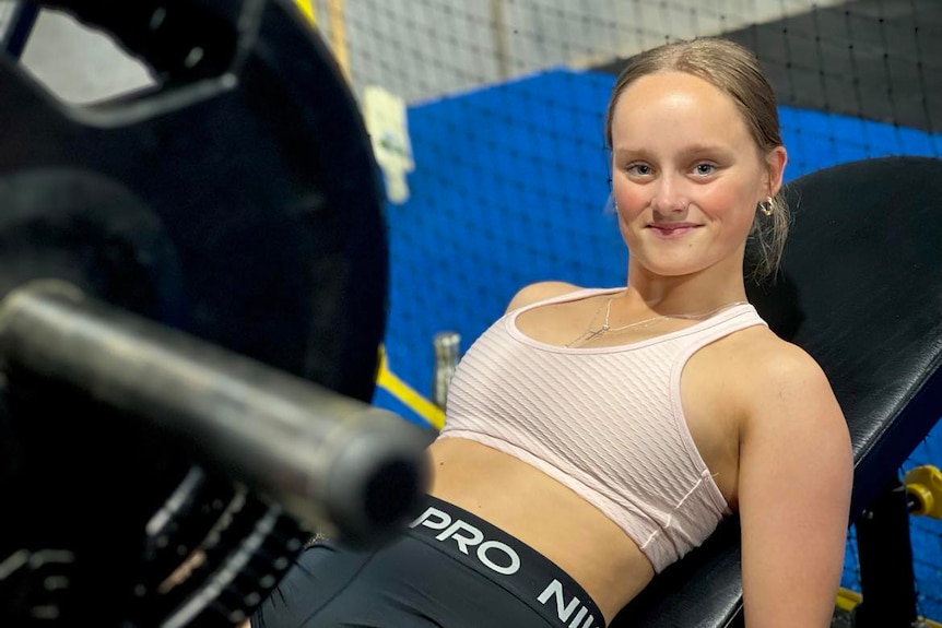 Girl smiling at camera while using gym equipment