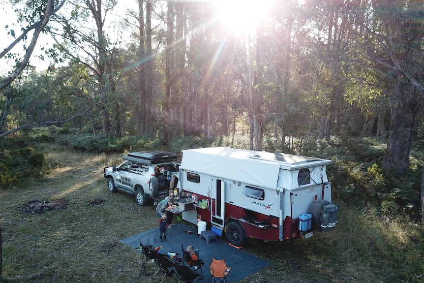 An aerial shot of the Murphys forest campsite shows Amy Murphy preparing a meal for their three boys outside their caravan.