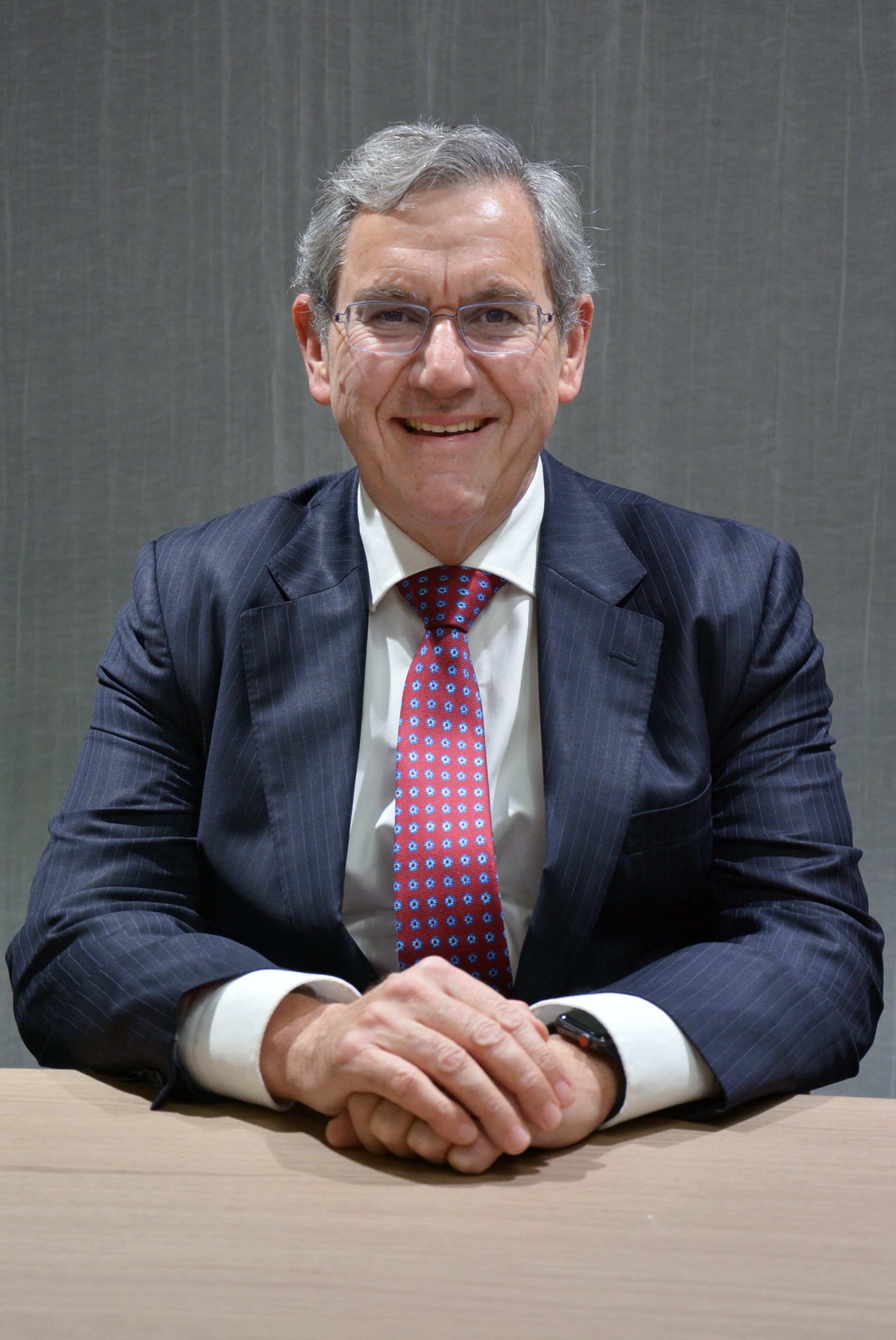 Foto da cadeira ASIC Joseph Longo de terno e gravata sorrindo.