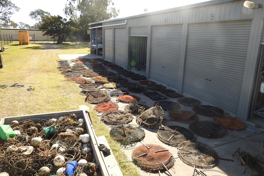 Crab pots in a skip bin and laid out next to a shed.