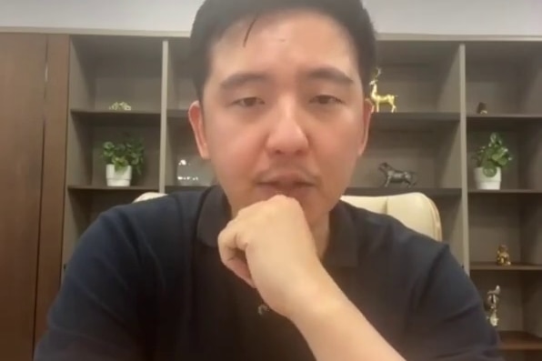 Man sitting at a desk wearing a dark blue polo shirt.