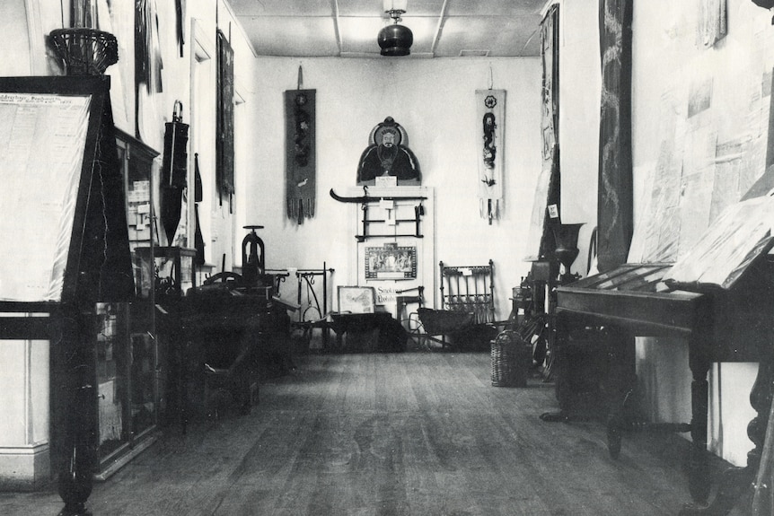 Black and white photo of a room containing cabinets and textiles
