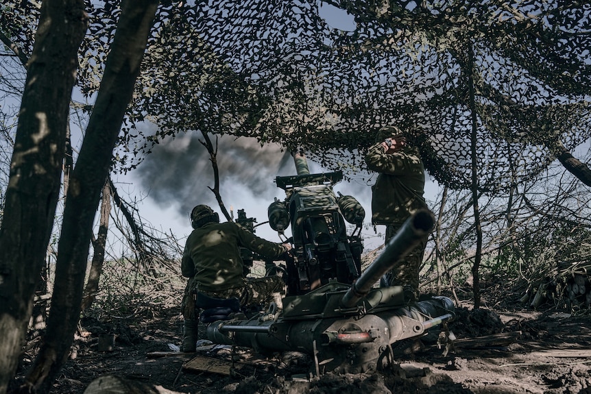Soldiers launch missiles hidden by camouflage tents and surrounded by trees