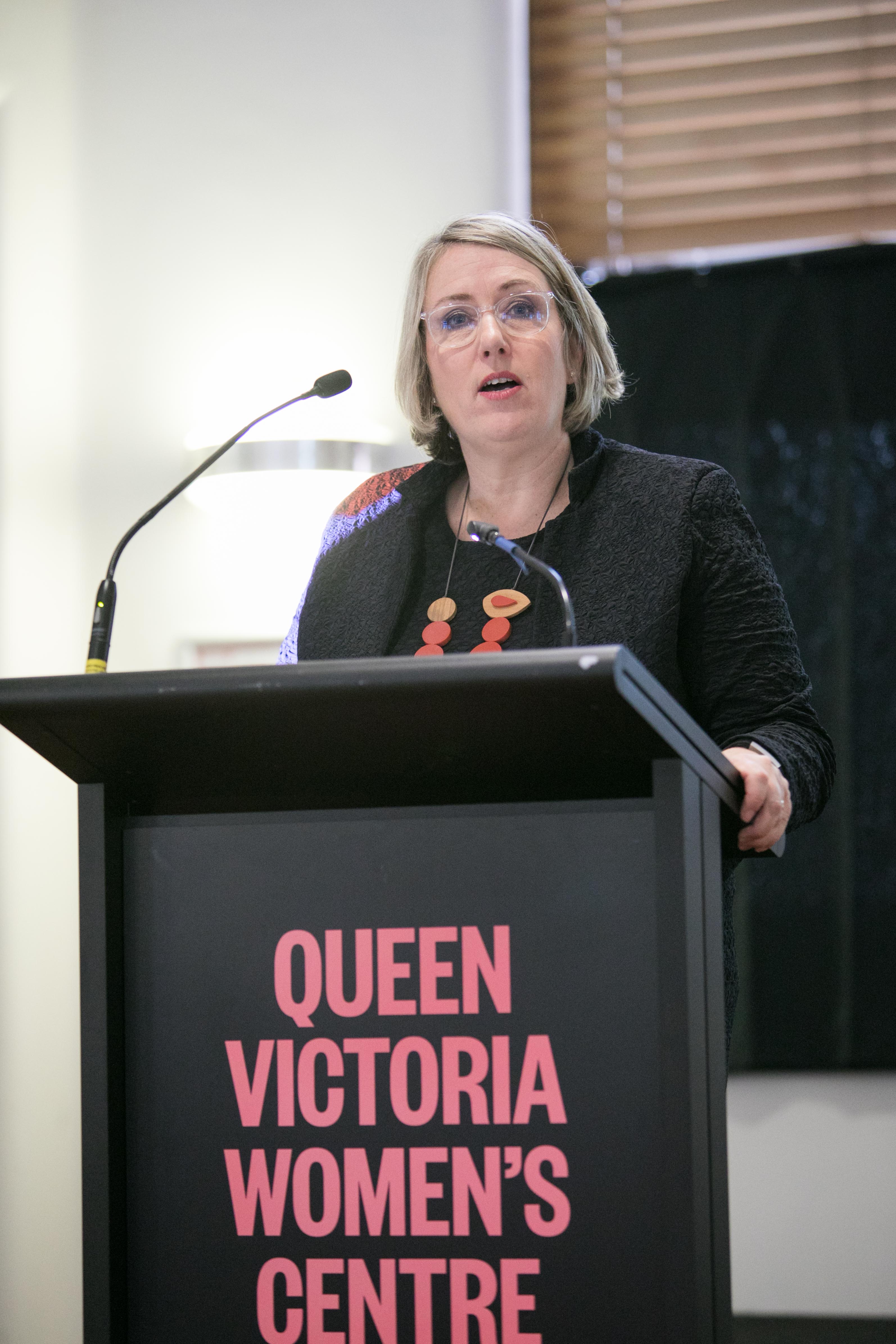 A woman delivers a speech at a lectern.